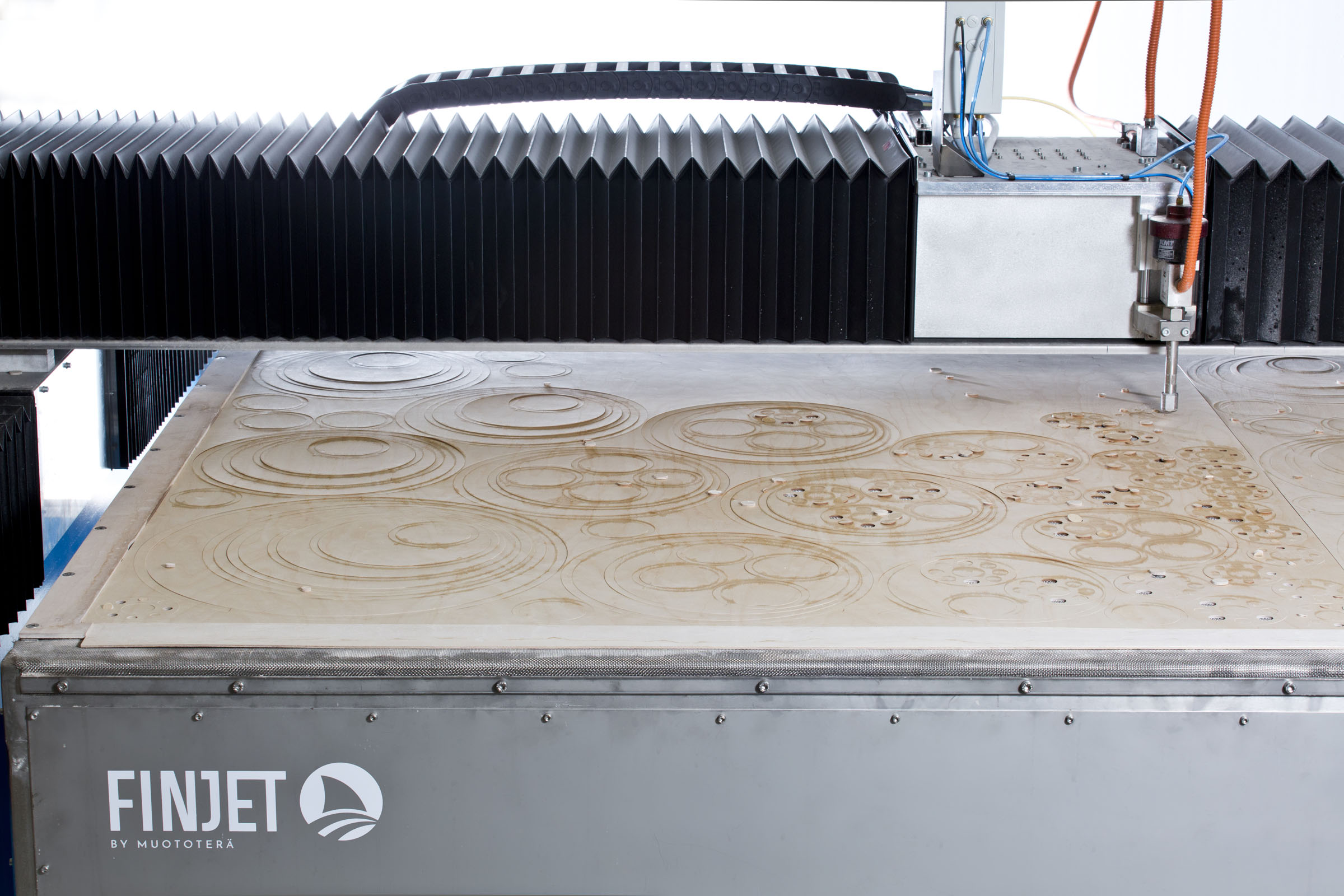 A waterjet cutting machine cutting rings out of a wooden board.