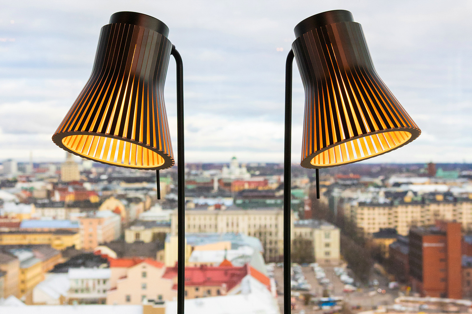 Two Petite table lamps in front of a window. A view of Helsinki in the background.
