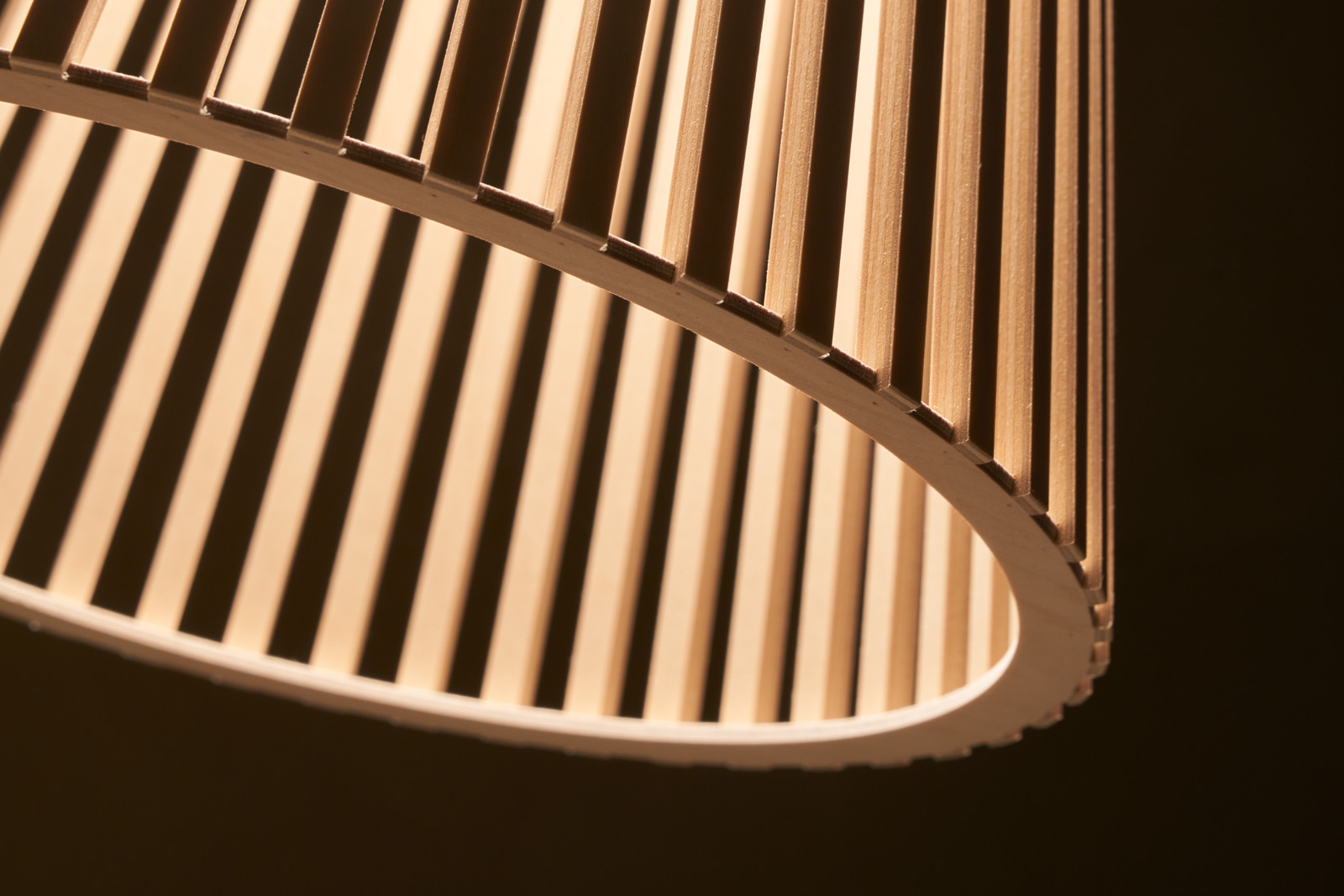 A close-up of a Secto pendant lamp, showing the lower ring in front of a dark background.