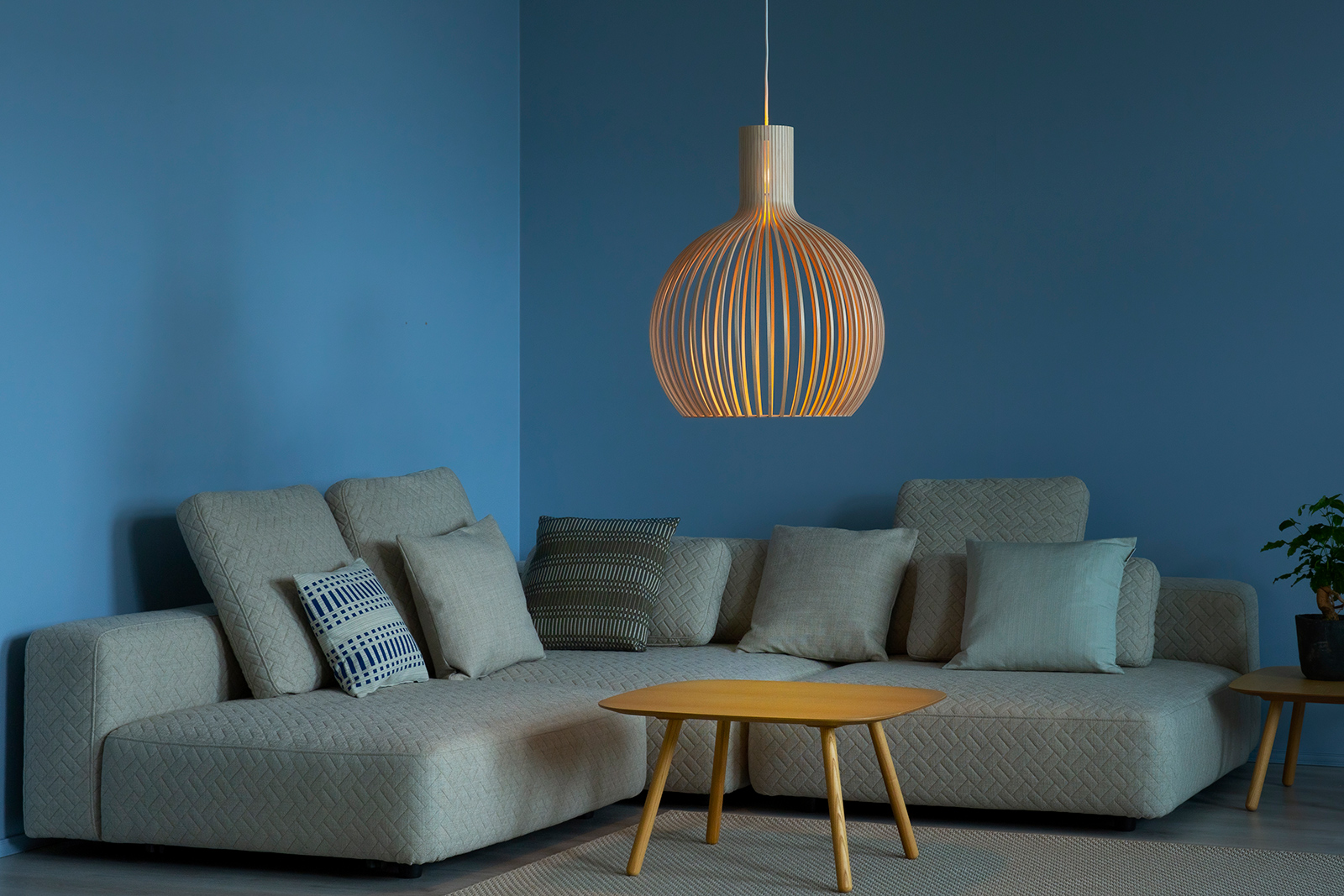 The Octo pendant lamp in birch, hanging over a coffee table.
