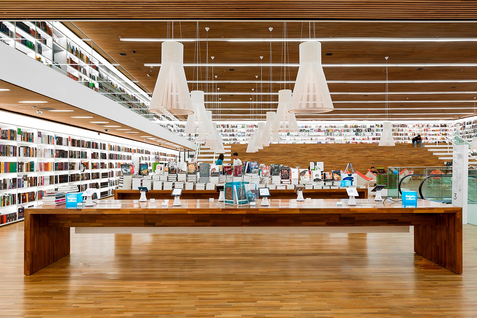 A large book store with white Magnum pendant lamps hanging over the tables.