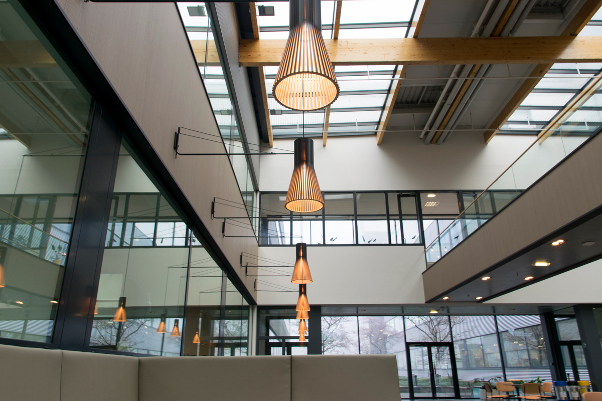 Pendant lamps hanging from suspension arms above a seating area.