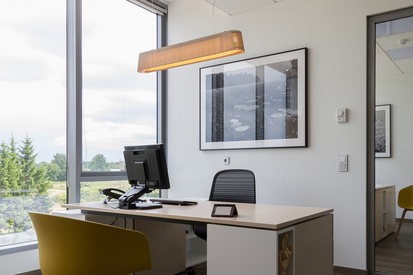 Ein Büro mit einer Pendelleuchte über dem Tisch und einem großen Fenster.