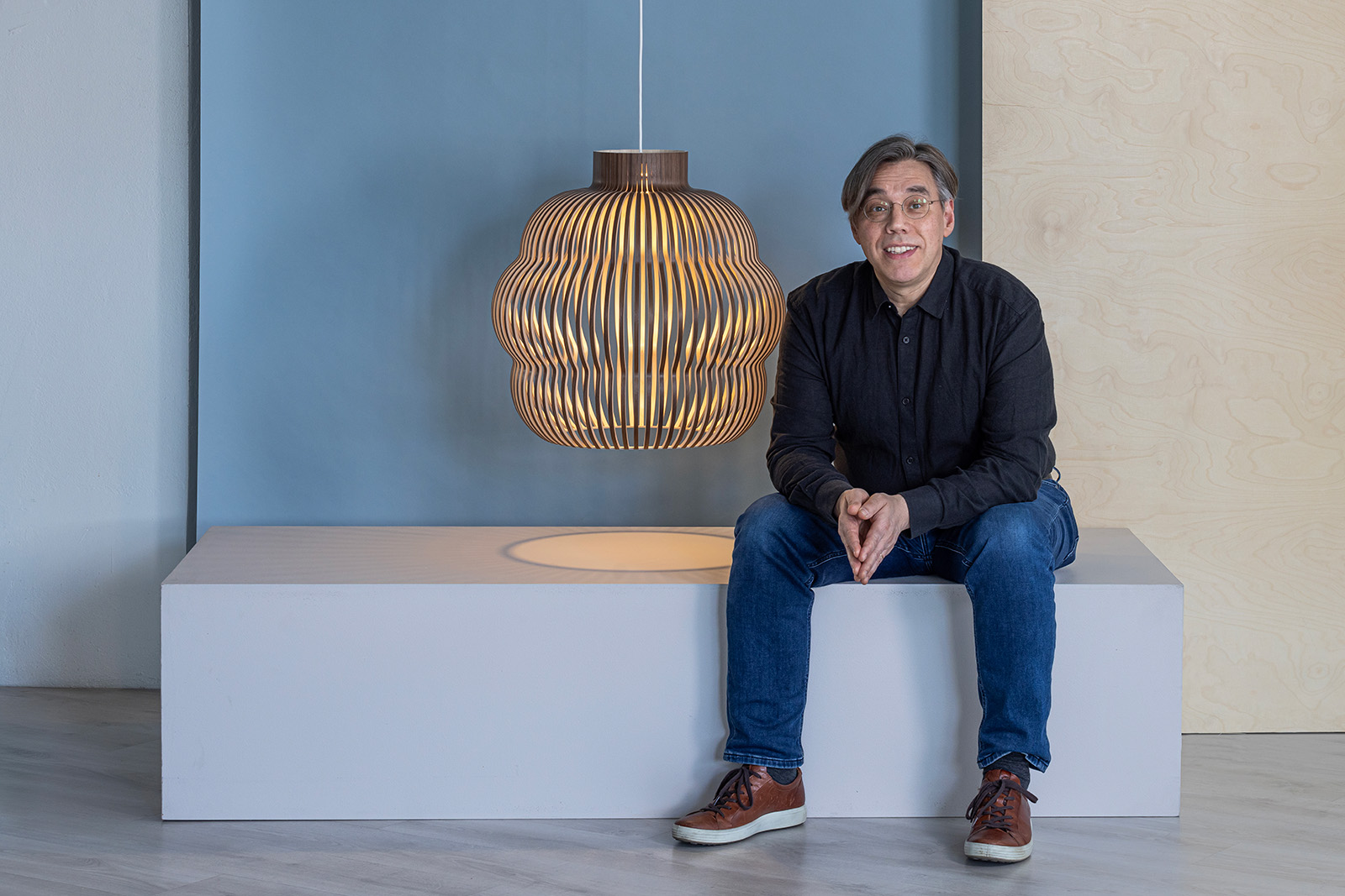 A man sitting next to a pendant lamp.