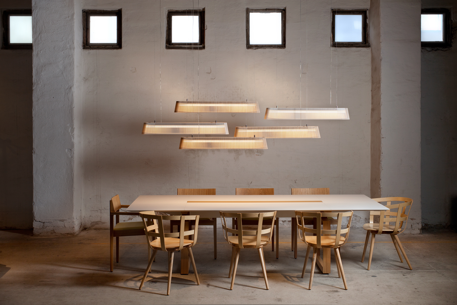 Several enlongated pendant lamps above a meeting table