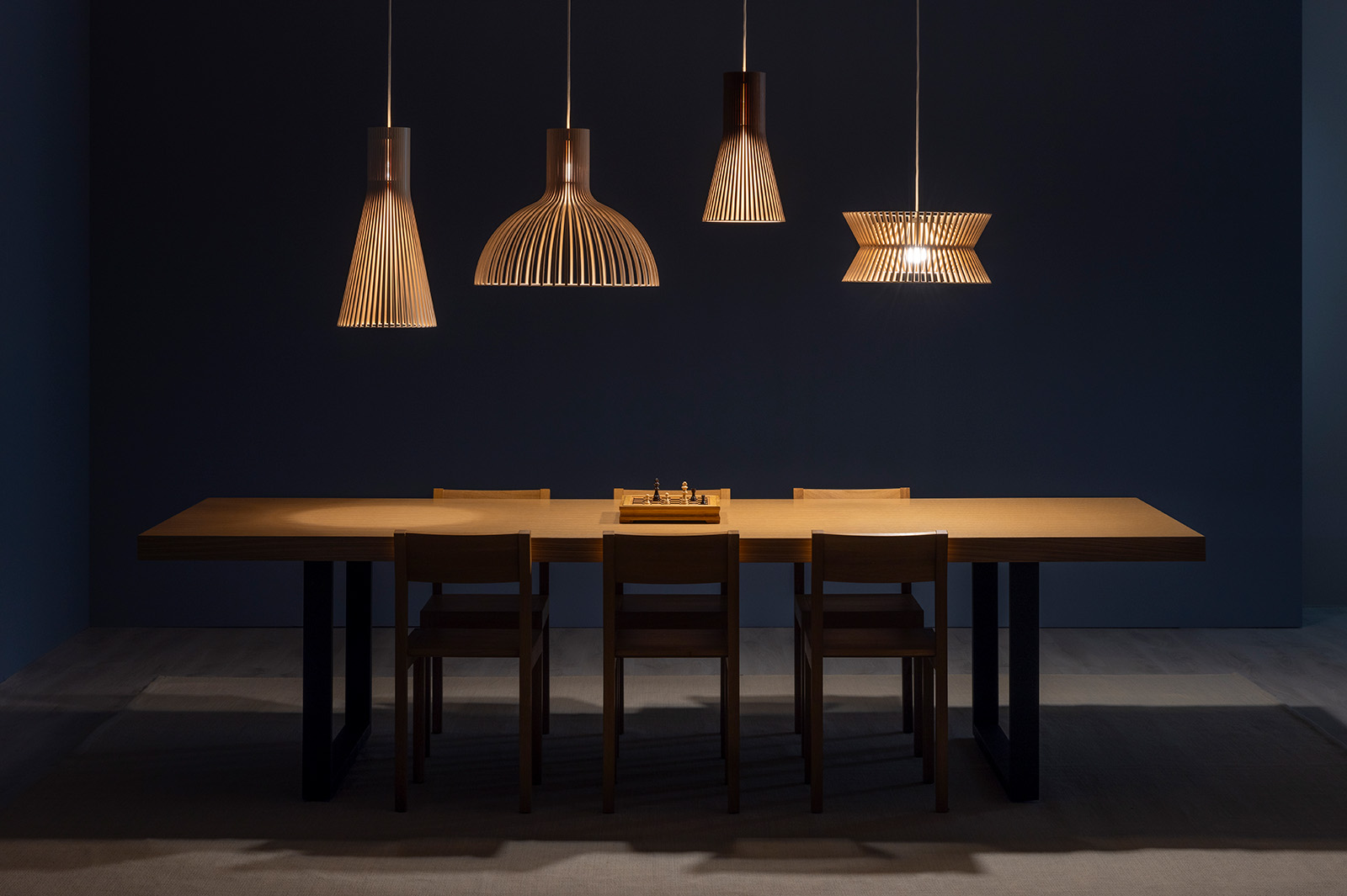 Several enlongated pendant lamps above a meeting table.