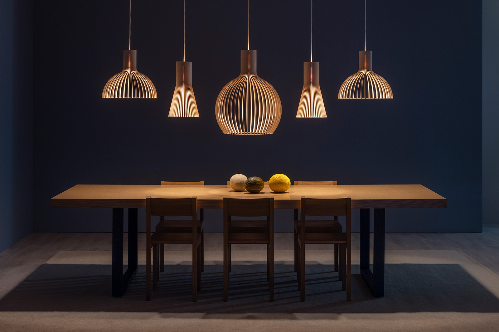 Several enlongated pendant lamps above a meeting table.