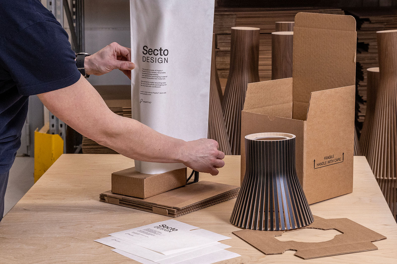 Une personne emballant une lampe dans l’usine de Secto Design.