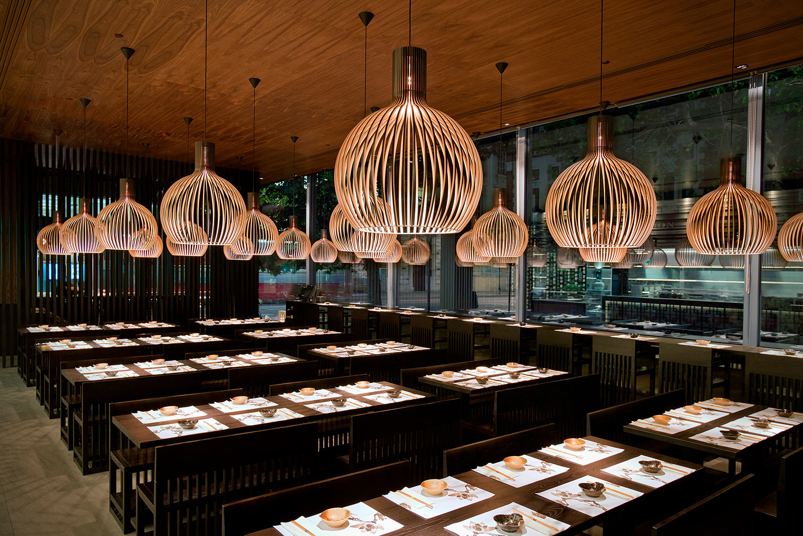 Un restaurant avec des suspensions Octo laminées noires au-dessus des tables.