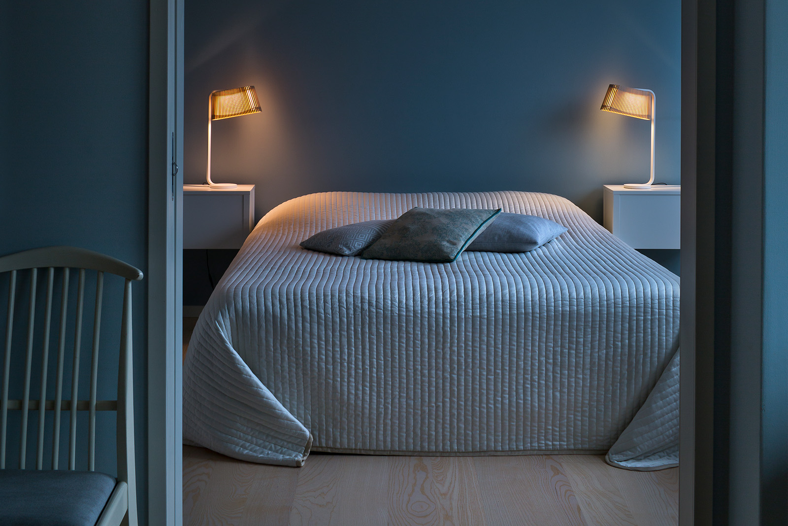 Une chambre à coucher avec un lit, des oreillers et des lampes de tables sur les tables de chevet.