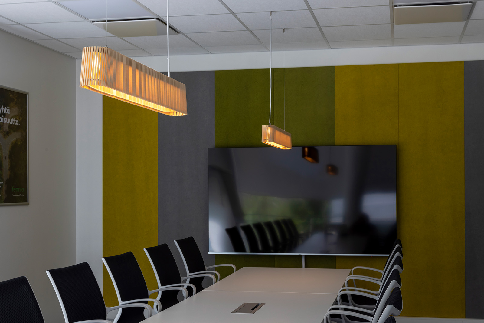 A meeting table lit by two elongated pendant lamps.